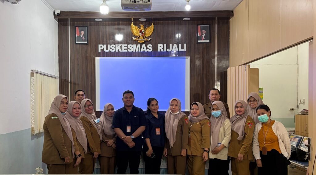 Staff and visitors pose under the Puskesmas Rijali sign